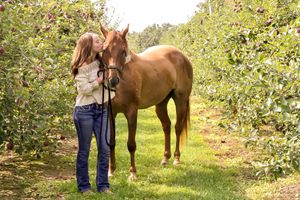 An affectionate kiss for this girl's horse. Apple trees line the pathway
