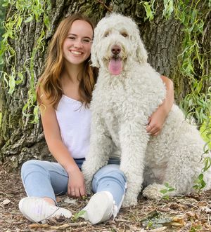 a girl and her adorable puppy pose lazily underneath a tree. The weeping willow branches frame them