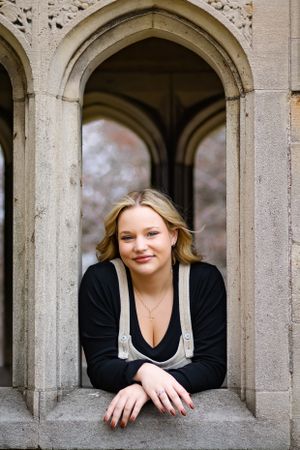 A gorgeous, timeless senior portrait. A girl poses out of stone arches