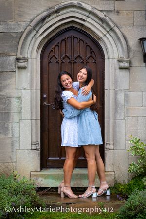 A stone mansion is the backdrop for this senior portrait These sisters embrace in front of a wooden door
