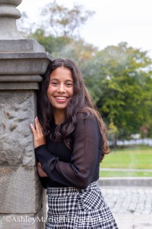 Using architecture in this senior portrait a girl poses against a stone pillar