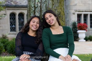 Senior portrait of sisters leaning against a tree and laughing