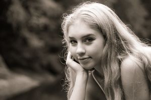 A vintage image captures light streaming behind the girl who poses with her head in her hands