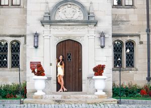 A stone mansion is the backdrop for this senior portrait The girl poses with attitude against a wooden door