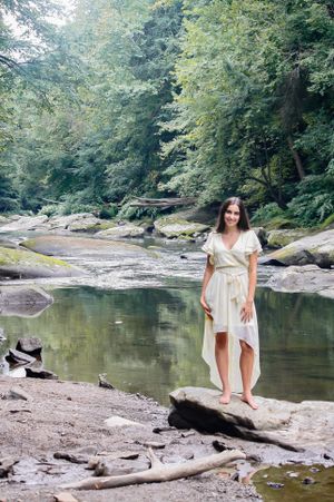 Using nature to capture this girls natural beauty, she poses on rocks and a stream flows behind her