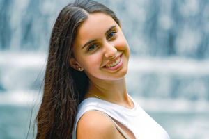 A waterfall and a stunning senior portrait of a girl smiling as the water flows behind her