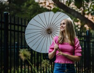 Posing with a parasol, the vibrancy of the sunset perfectly frames this senior as she poses for her portrait
