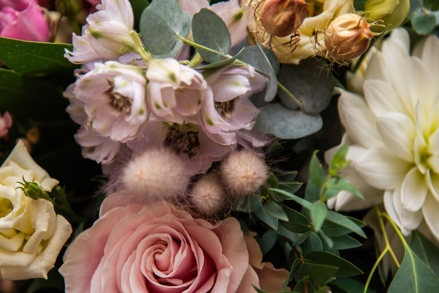 Lush floral arrangement with pink and cream roses mixed with greenery.