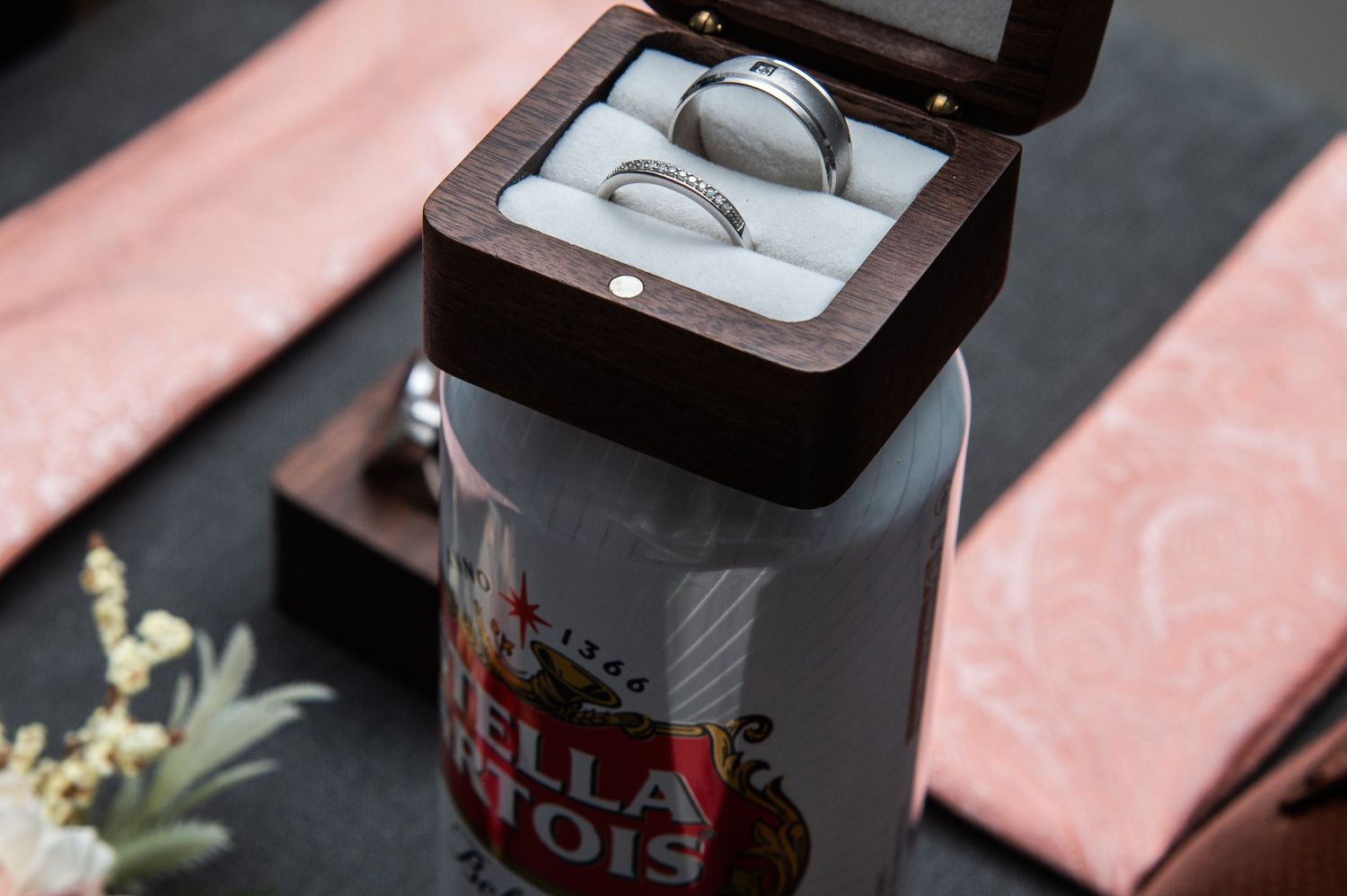 Ring box with custom wedding band displayed on pink fabric.