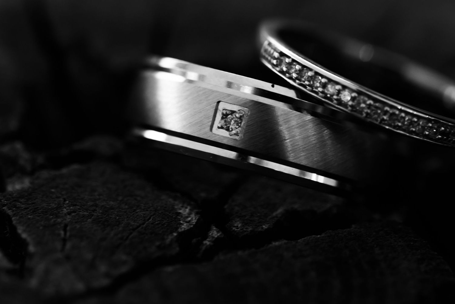 Artistic black and white detail shot of wedding rings with dramatic lighting.
