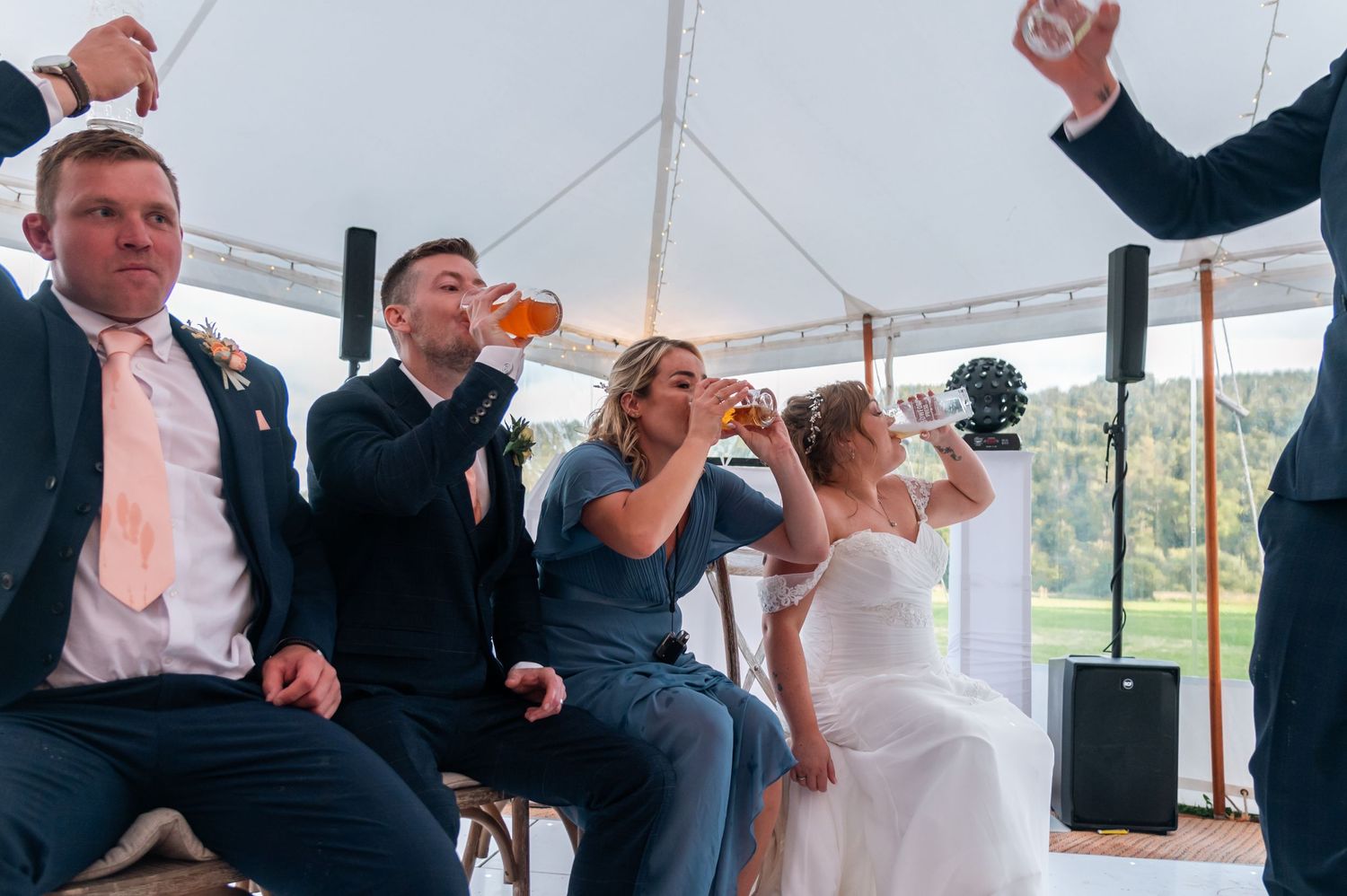 Wedding guests enjoying drinks and dancing during evening reception celebration.