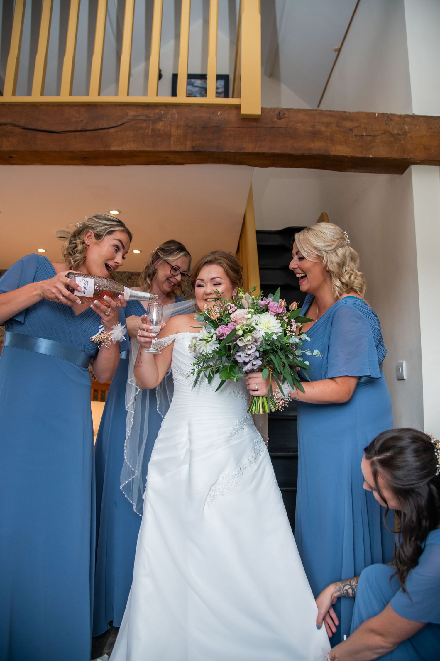 Wedding party wearing blue dresses helping with bridal preparations.