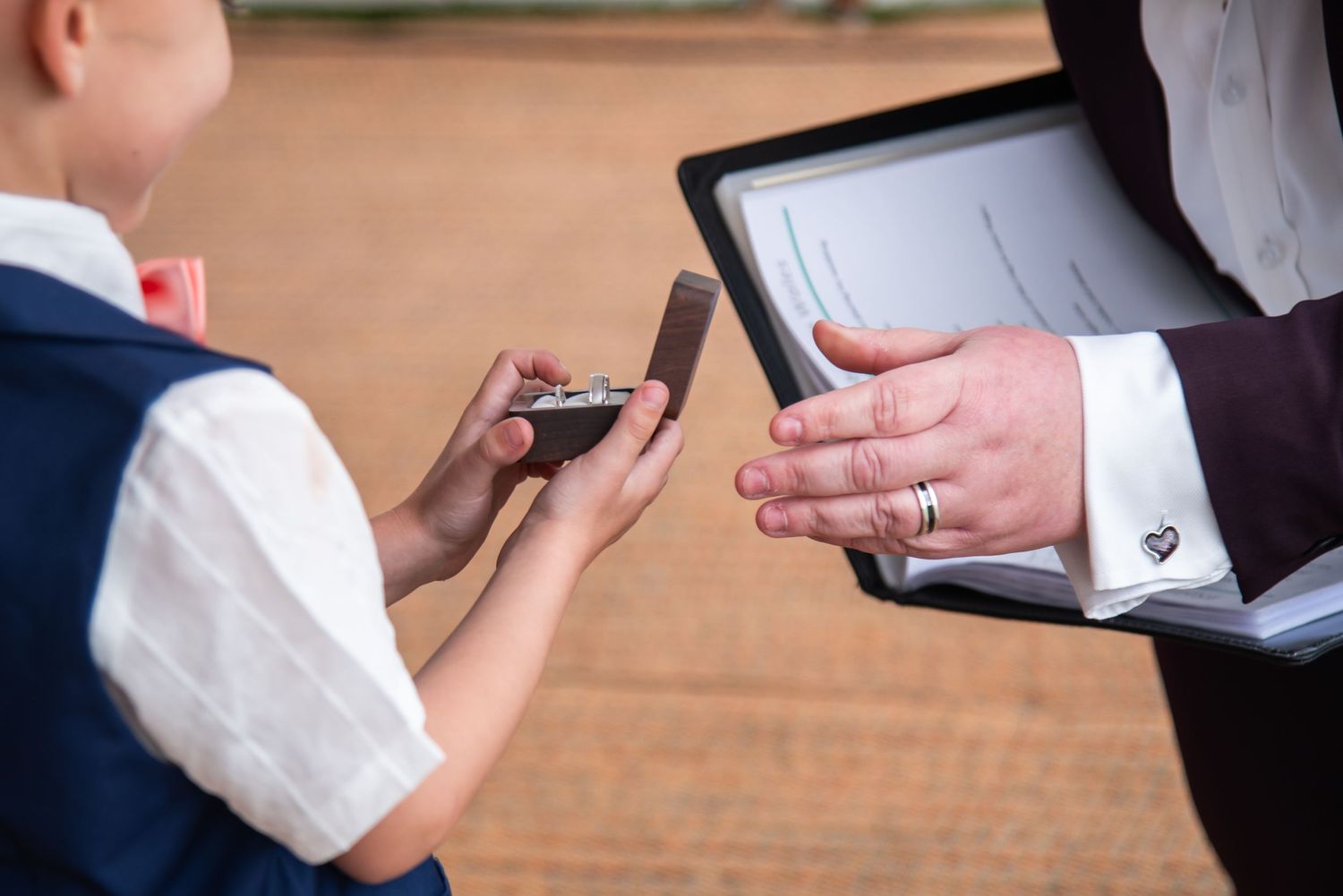 Close-up shot of hands exchanging rings during a wedding ceremony.
