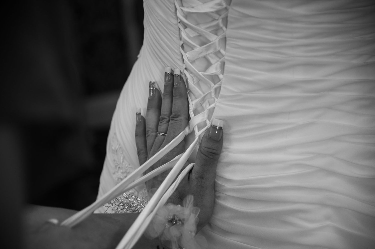 Close-up detail of a white wedding dress showing ruched fabric pattern.
