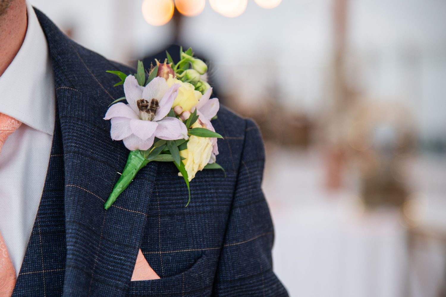 Classic navy suit jacket with delicate white and pink floral boutonniere details.
