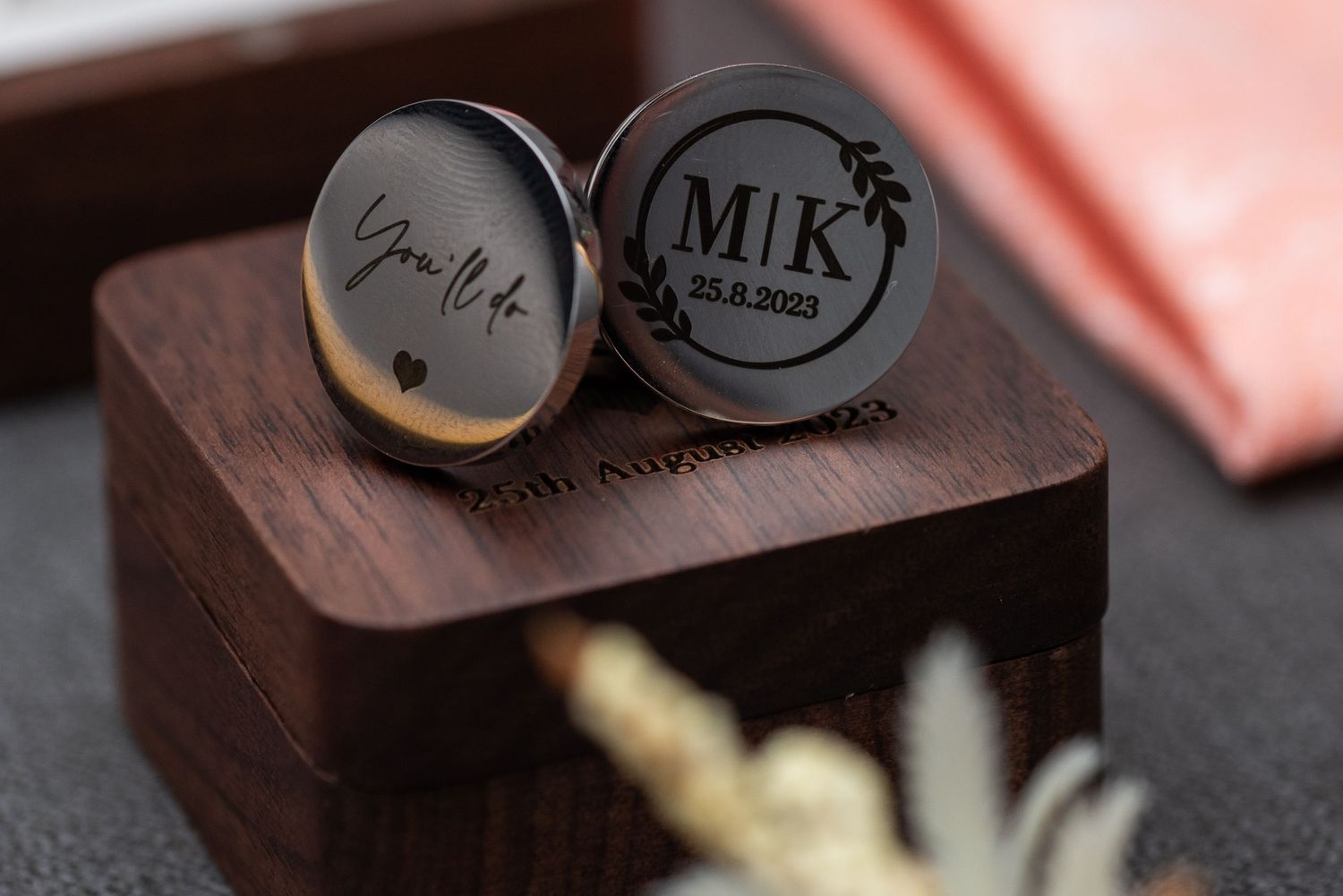 Close-up shot of a wedding ring being displayed in a black ring box against a wooden surface.