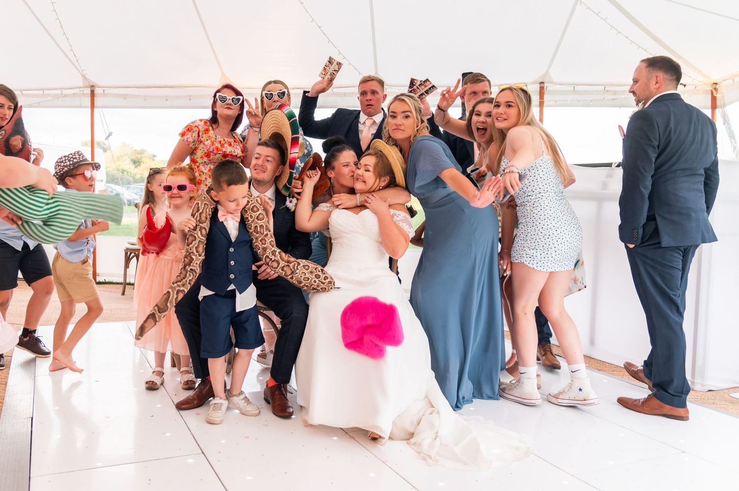 Wedding guests dancing and celebrating in white tent reception space.