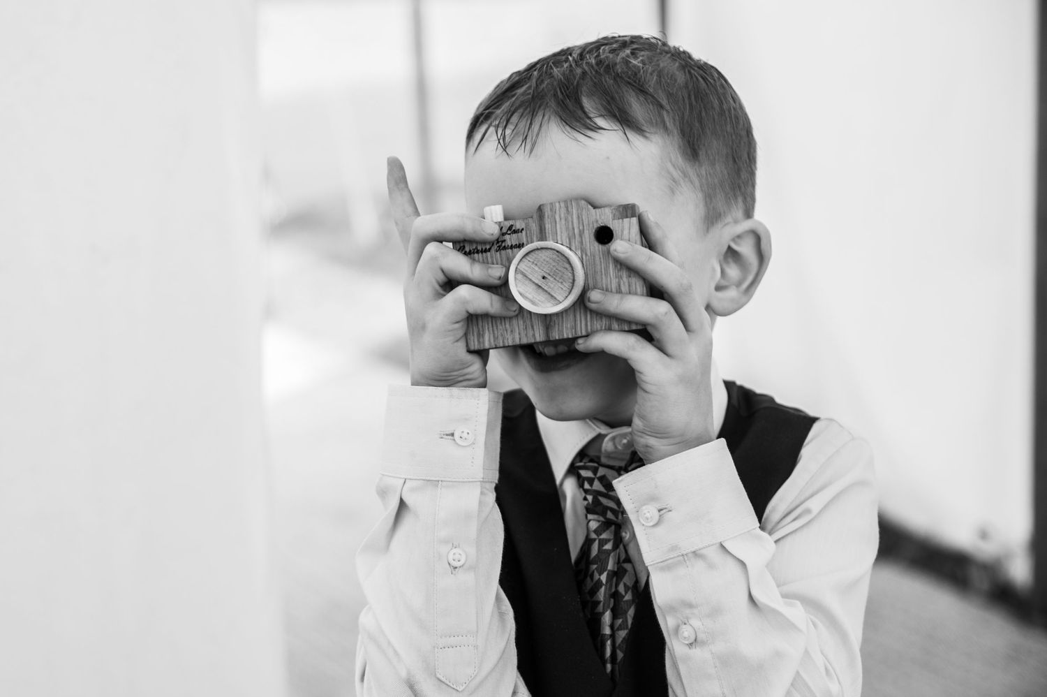 Black and white portrait of young children playing with cameras at a wedding.