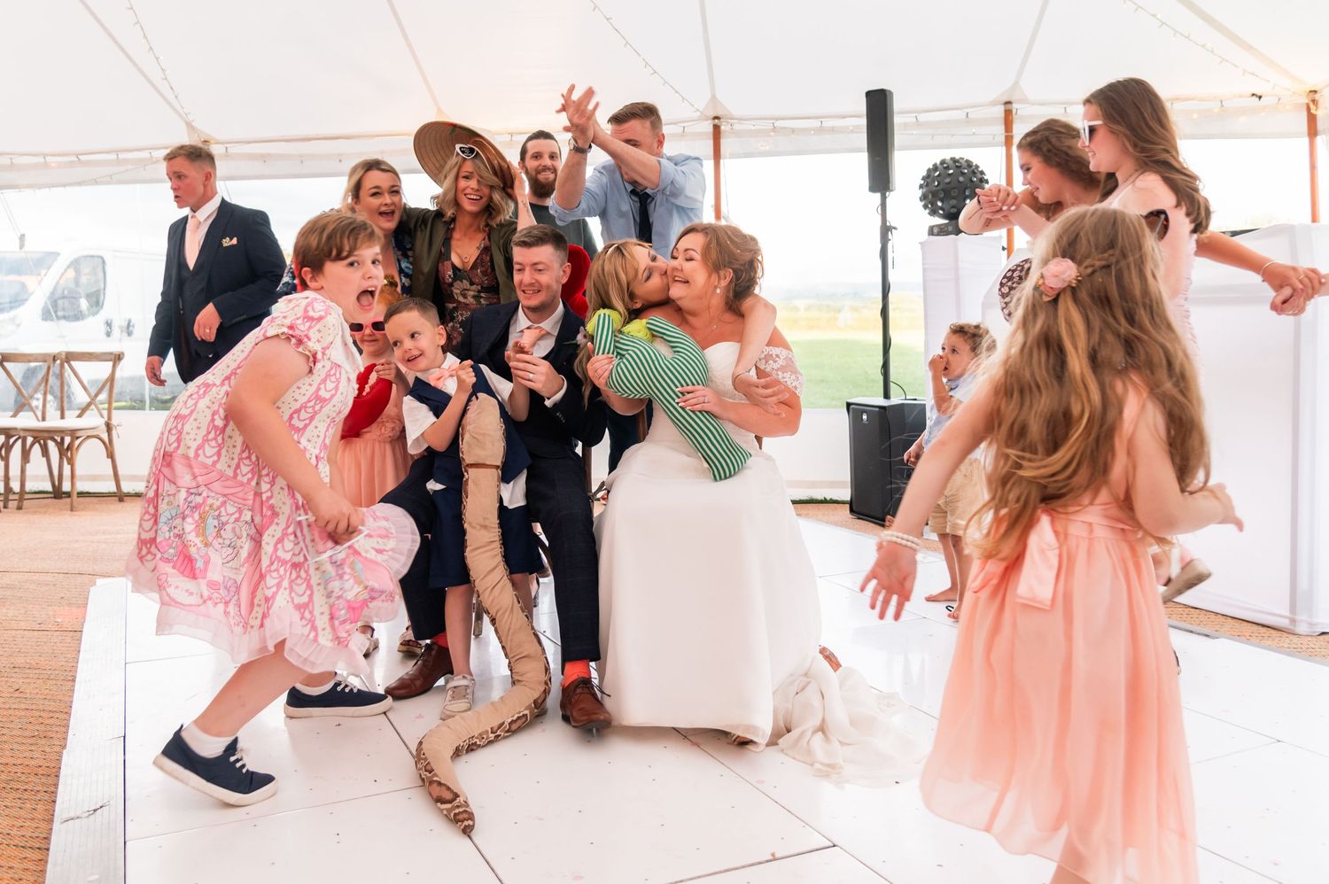 Children dancing and playing at wedding reception in light-filled tent.