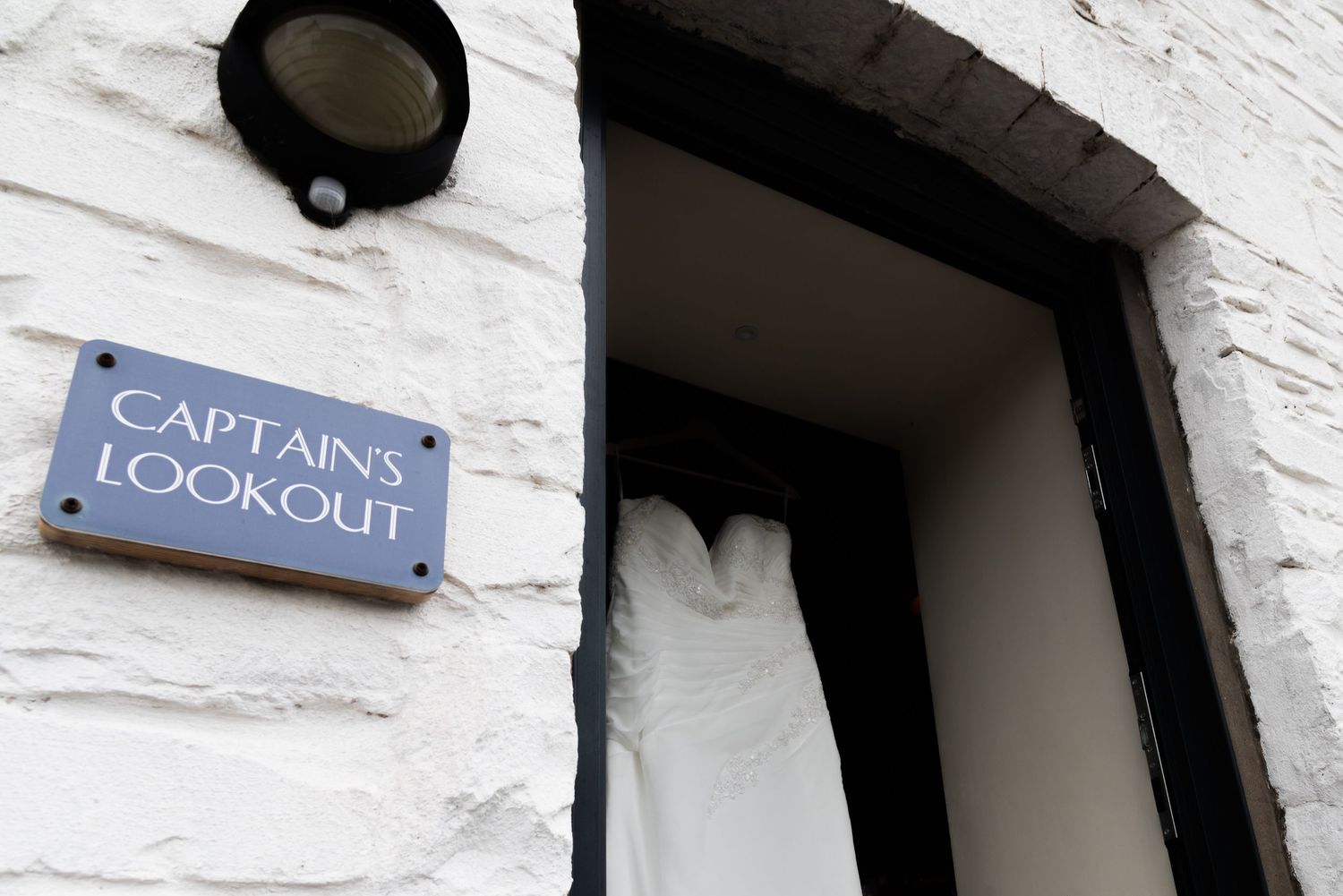 Exterior view of rustic white building with signage showing 'Captain's Lodge' in navy blue lettering.