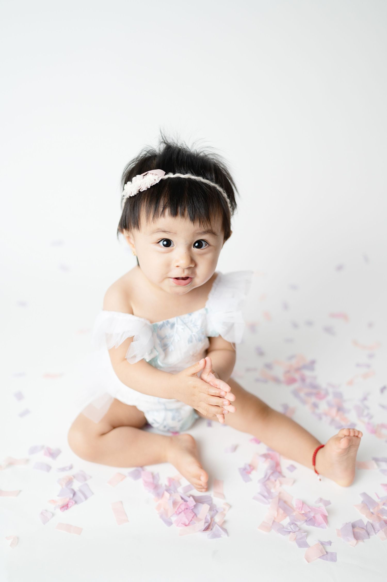 Delicate portrait on white background with lace dress and headband.