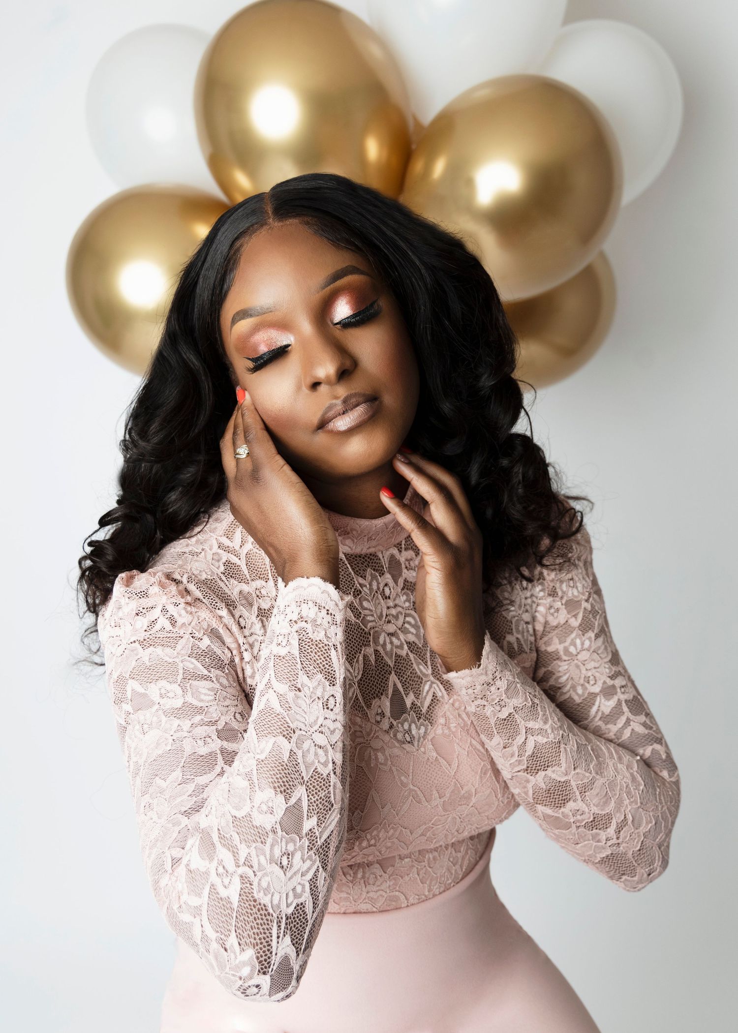 Glamorous portrait with pink lace dress against white and gold balloon backdrop.