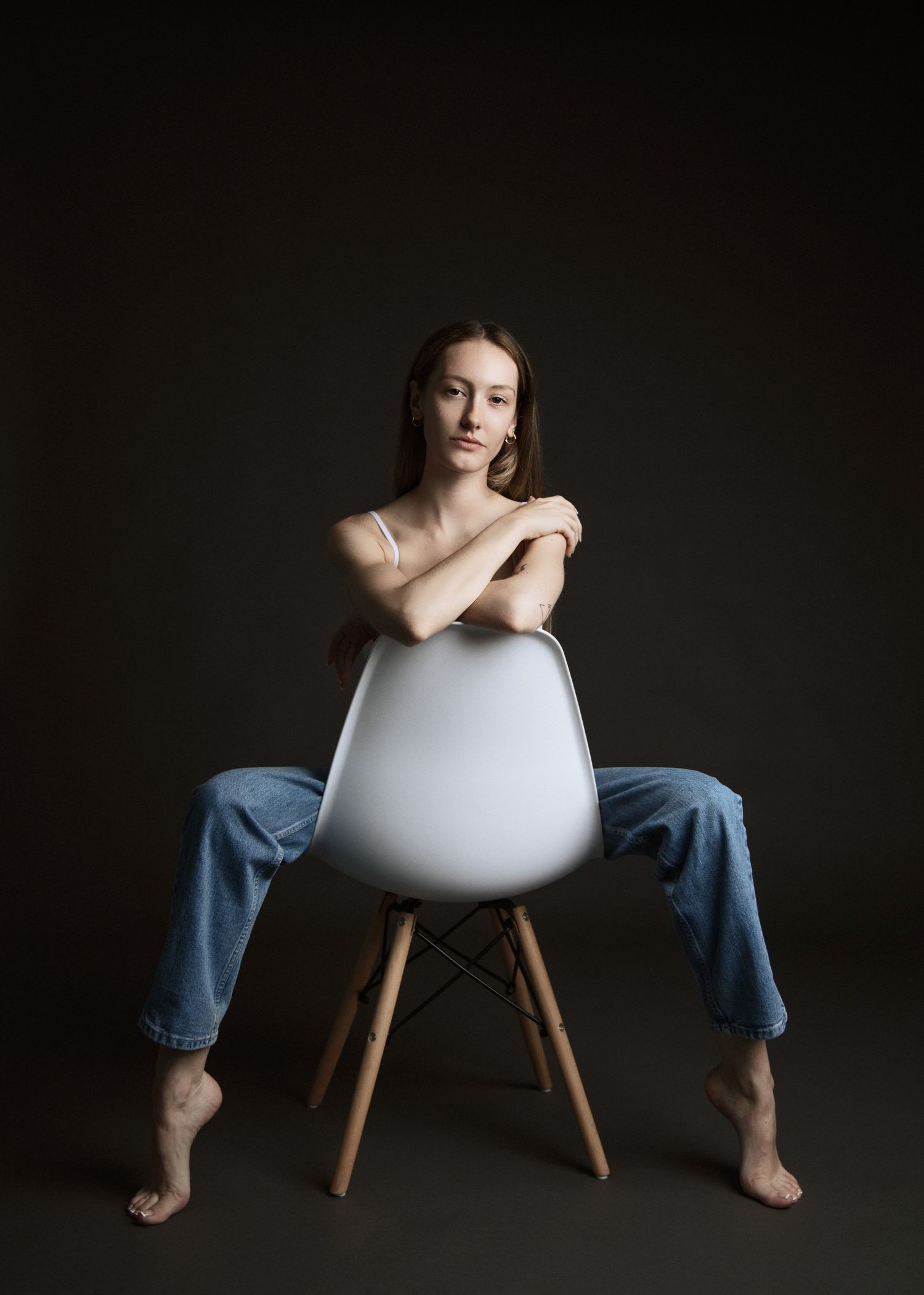 Artistic portrait on modern white chair against dark background in minimalist style.