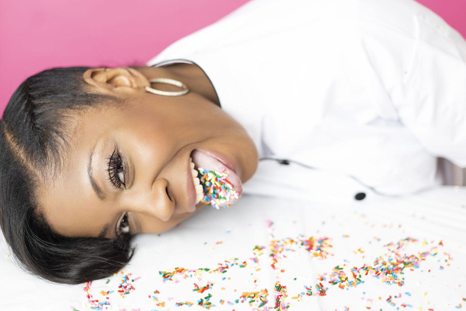 Studio beauty portrait with glitter makeup against pink background.
