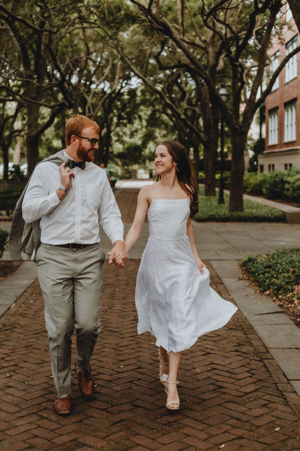 A couple runs down a tree-lined path