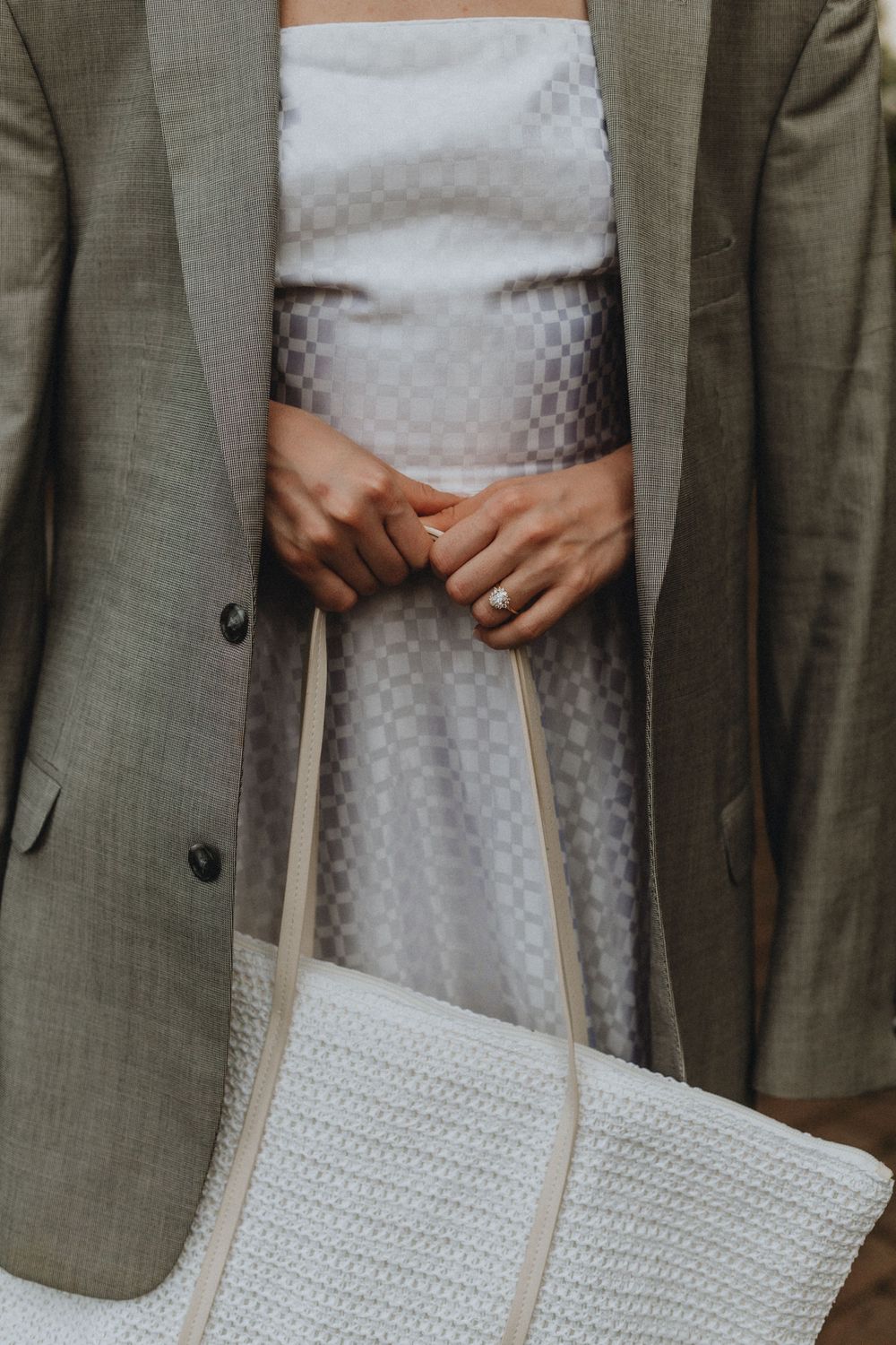 A closeup of a woman in a white dress holding a handbag