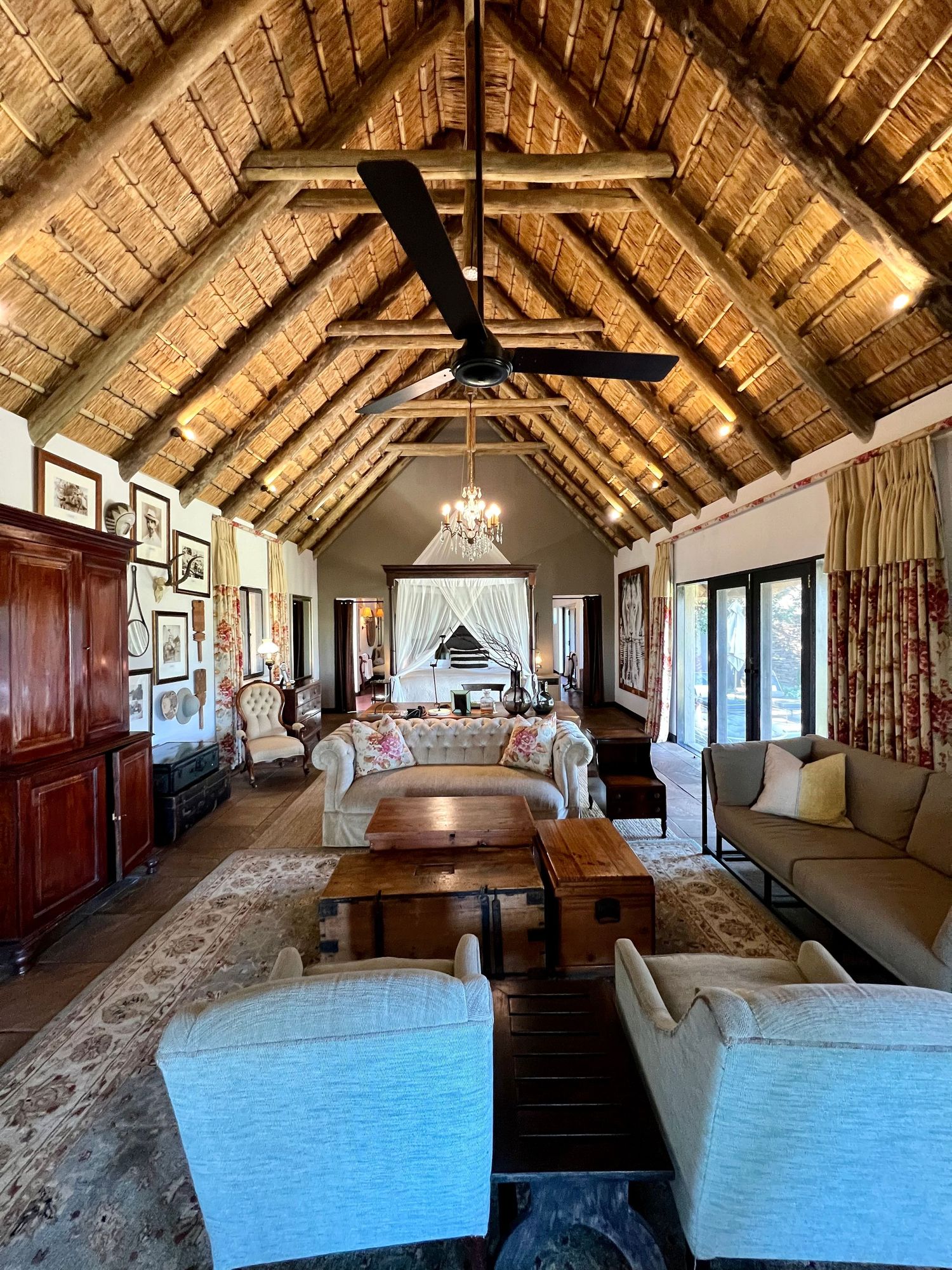 Elegant lodge-style room with vaulted thatched ceiling, chandelier and comfortable seating arrangement.