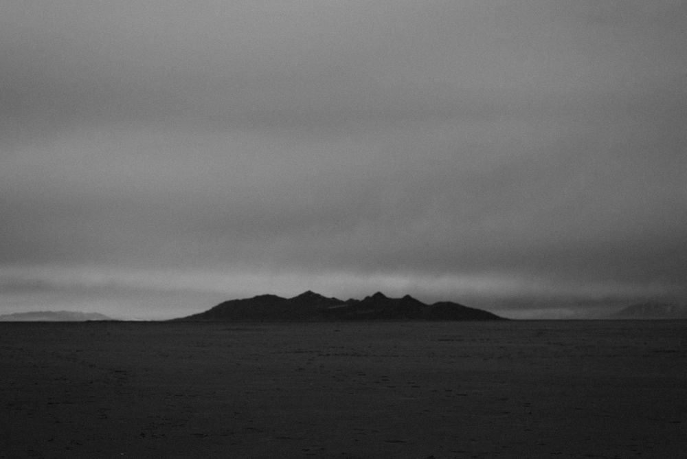 Minimalist black and white landscape of mountains under an overcast sky.