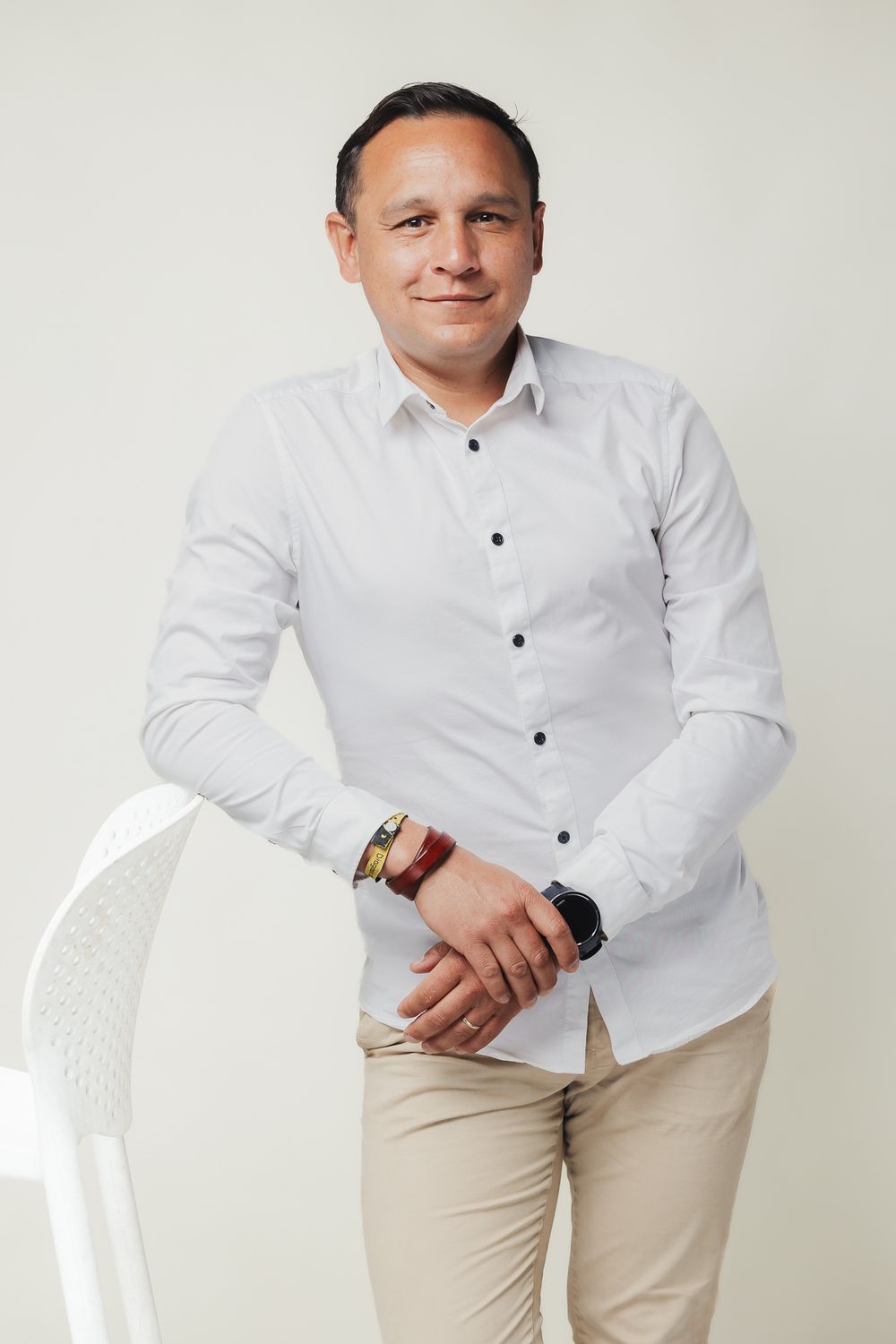 Professional portrait against white background in formal white shirt and khaki pants.
