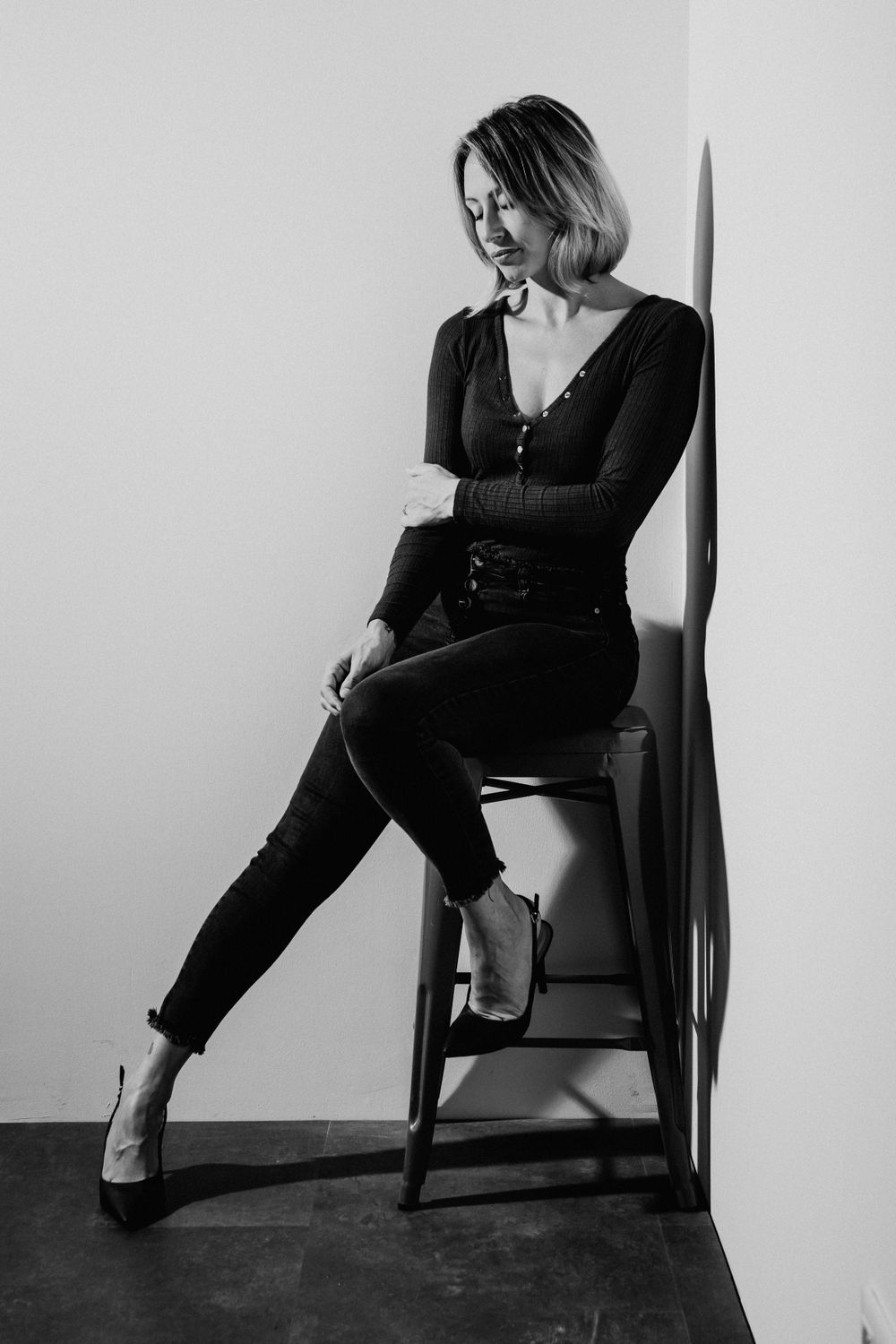 Black and white portrait series showing dramatic poses in a chair against a minimalist background.