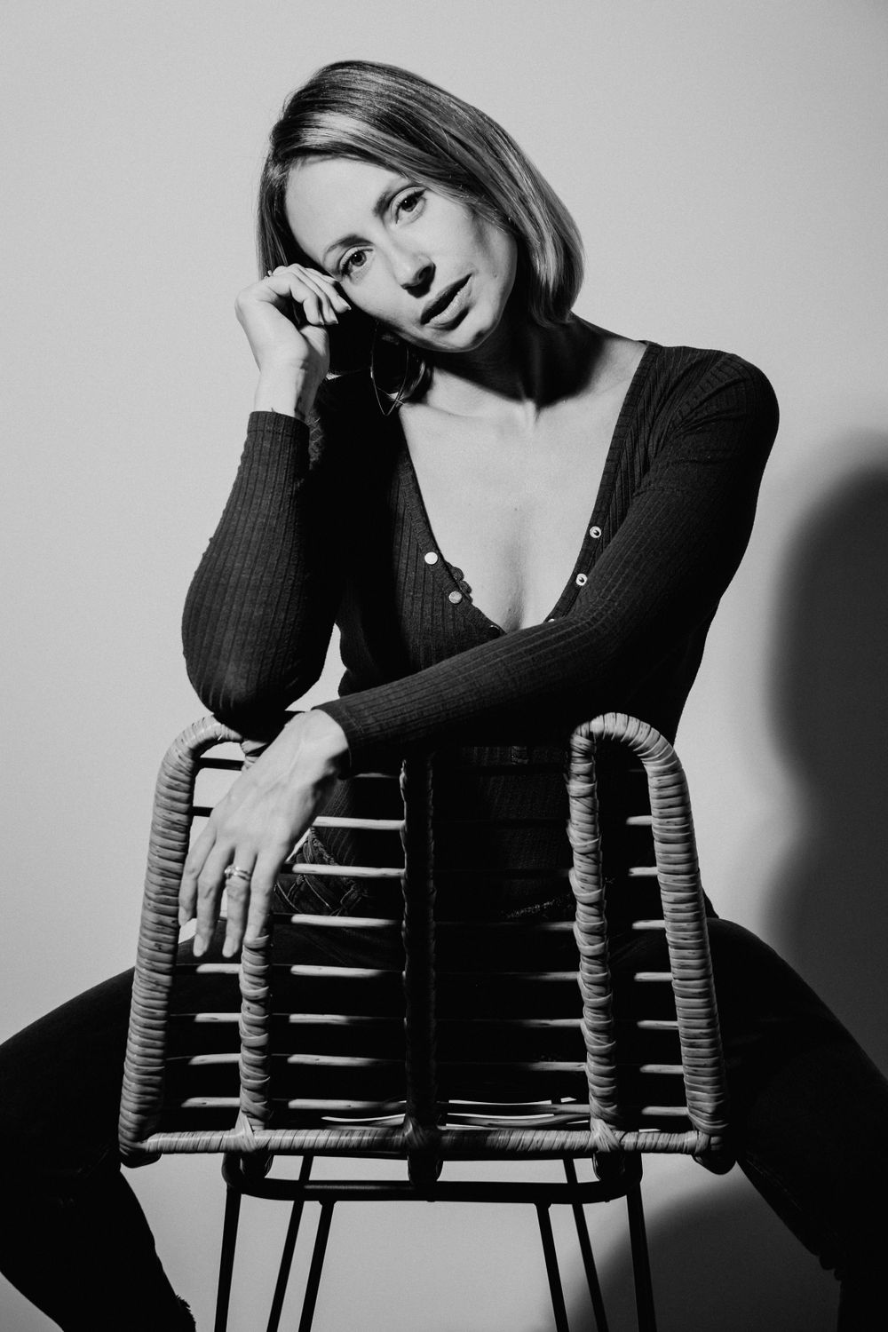 Artistic black and white photo series featuring moody poses on a wooden chair.