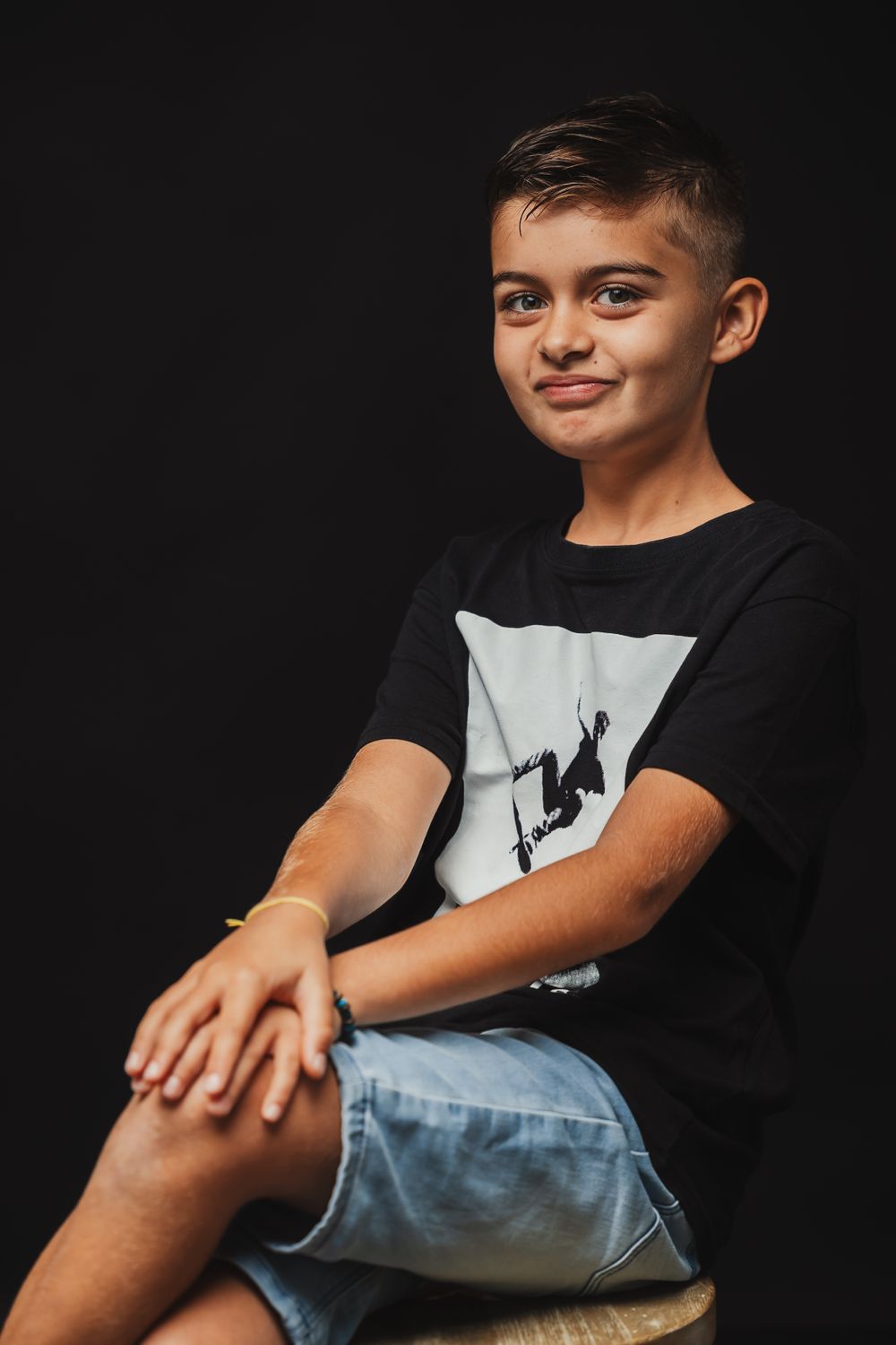 Series of casual poses showing a child in black shirt and jeans against dark background.