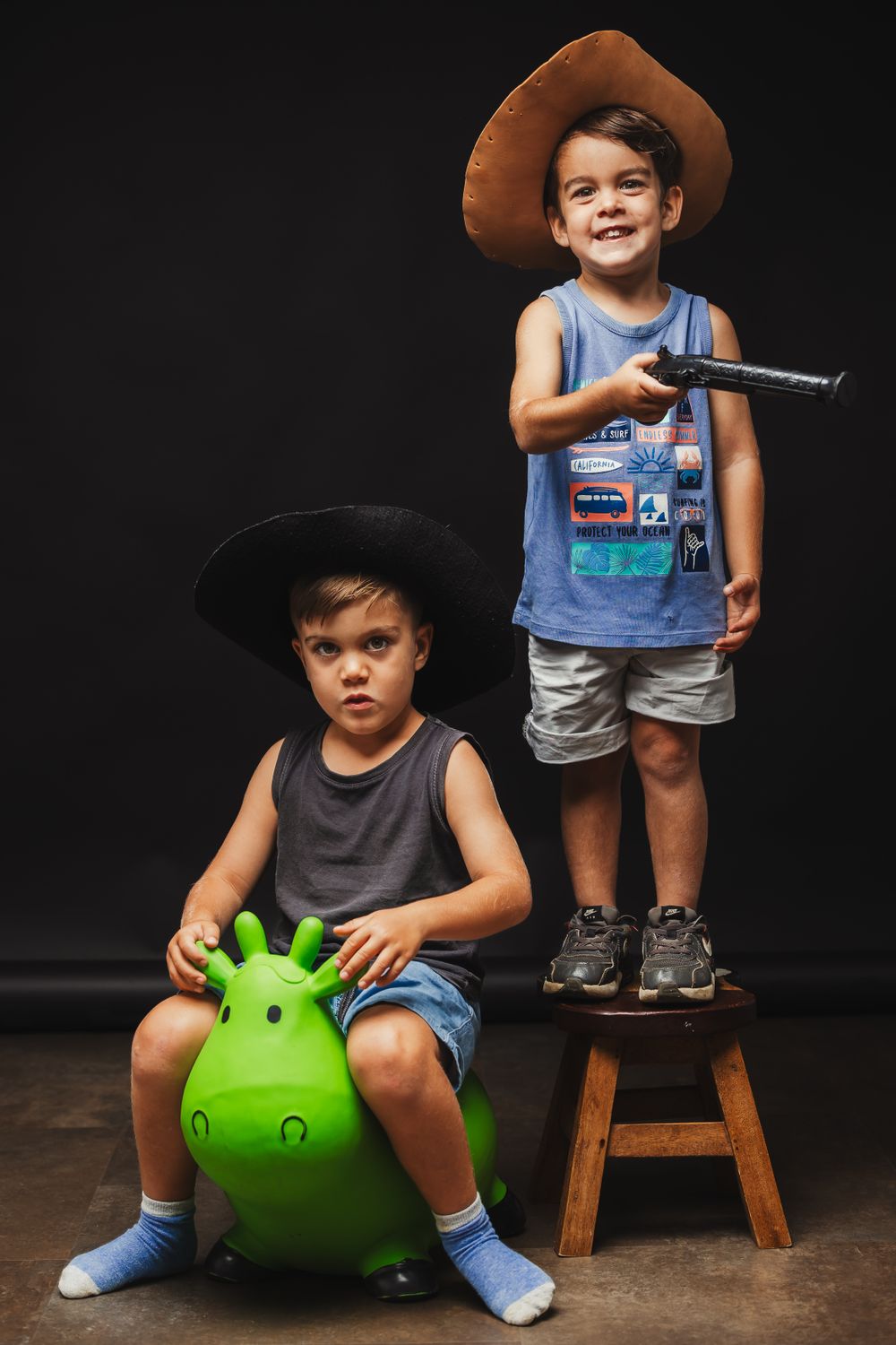 Children playing with toys including a green bouncy ball and cowboy hat against dark background.