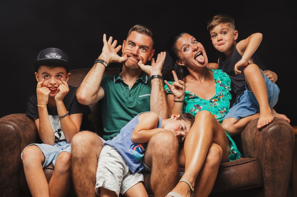 Group of friends lounging casually together on a couch making playful expressions.