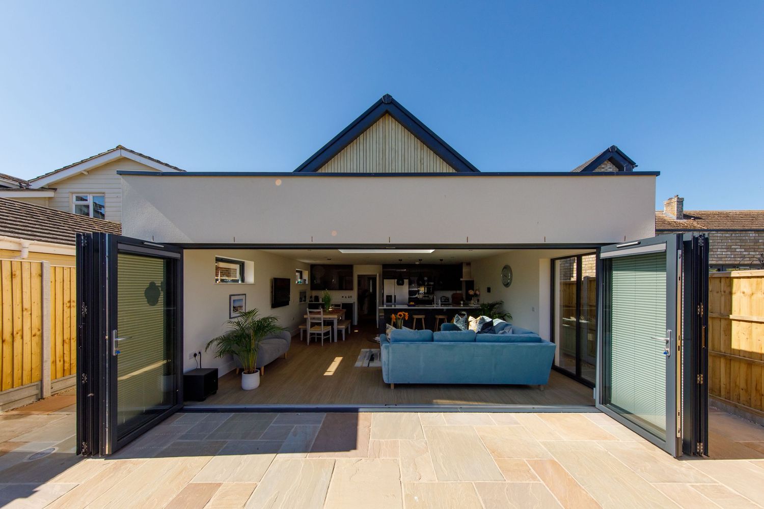 Modern home extension with bi-fold doors opening to a patio area showing indoor-outdoor living space.