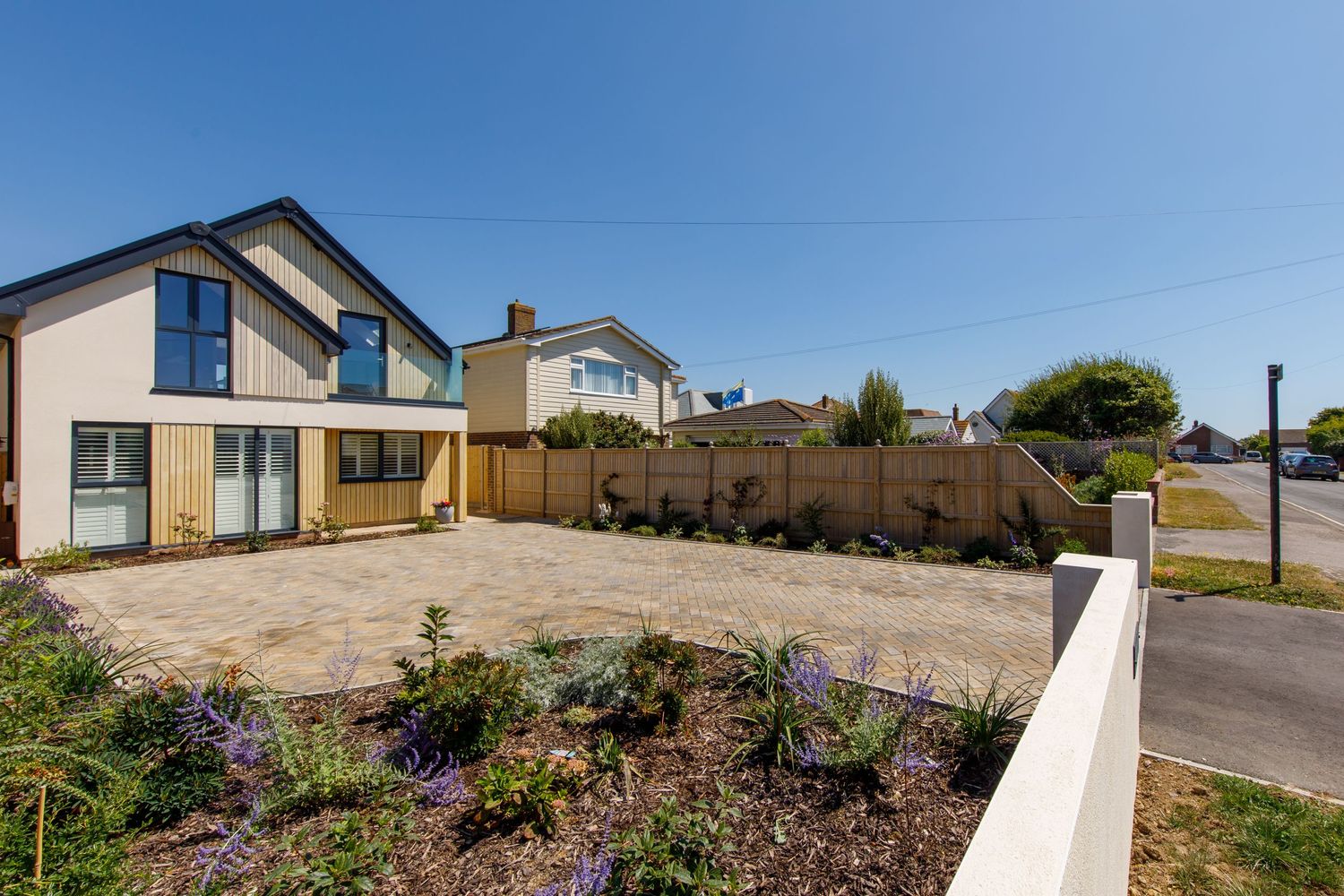 Modern two-story house with landscaped front garden and paved driveway.