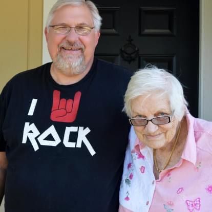 Two people posing by a black door, one wearing an 'I Rock' t-shirt and another in a pink butterfly blouse.