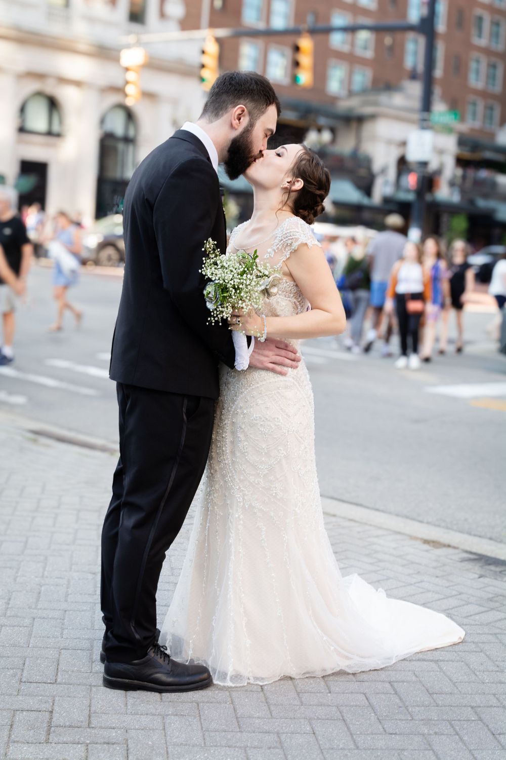 A romantic wedding couple shares a kiss on a city street corner during their special day.