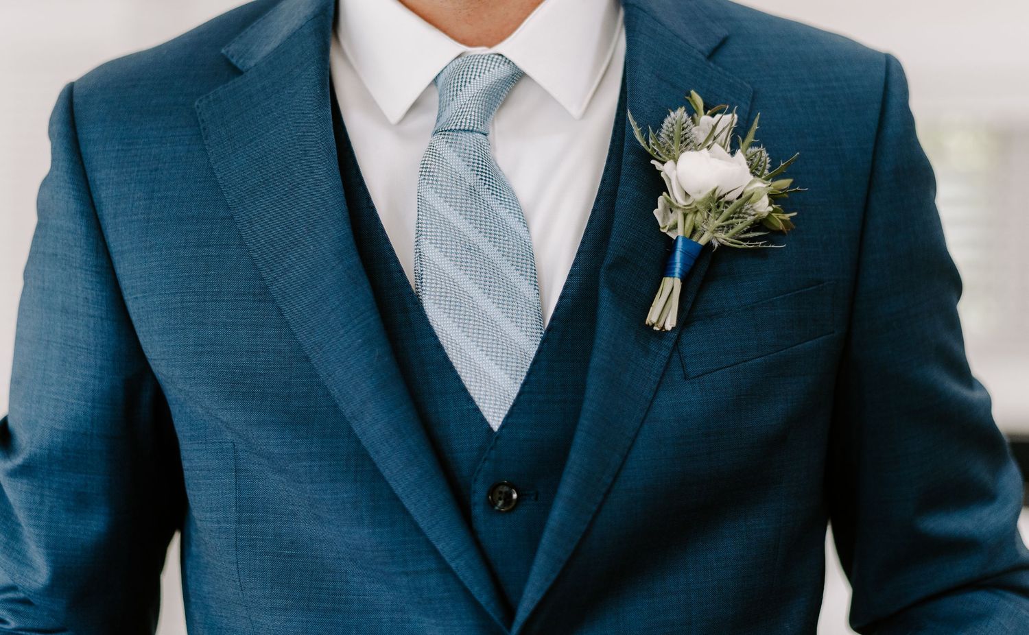 Row of groomsmen in matching navy blue suits with light blue ties and boutonnieres.