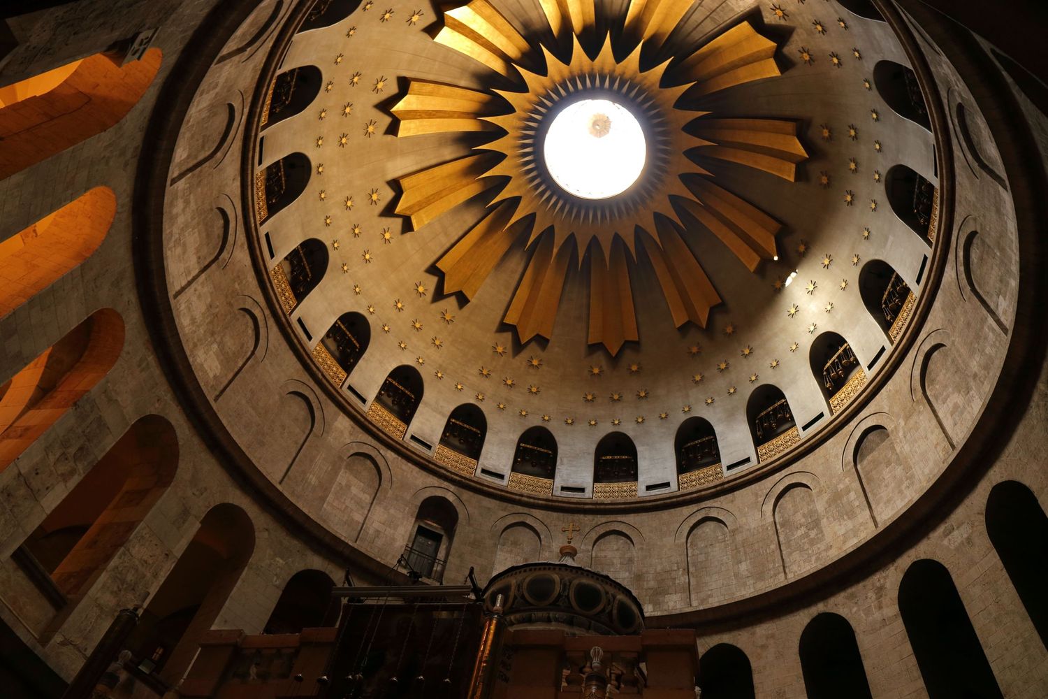 Interior view of an ornate domed ceiling with intricate patterns and a central skylight in a religious building.