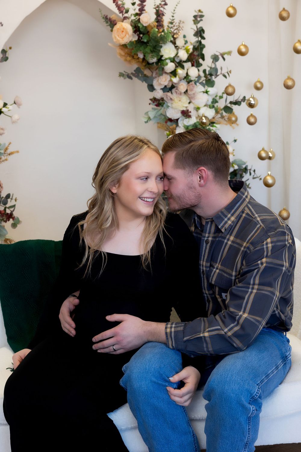Intimate moment captured during holiday maternity session with floral backdrop.
