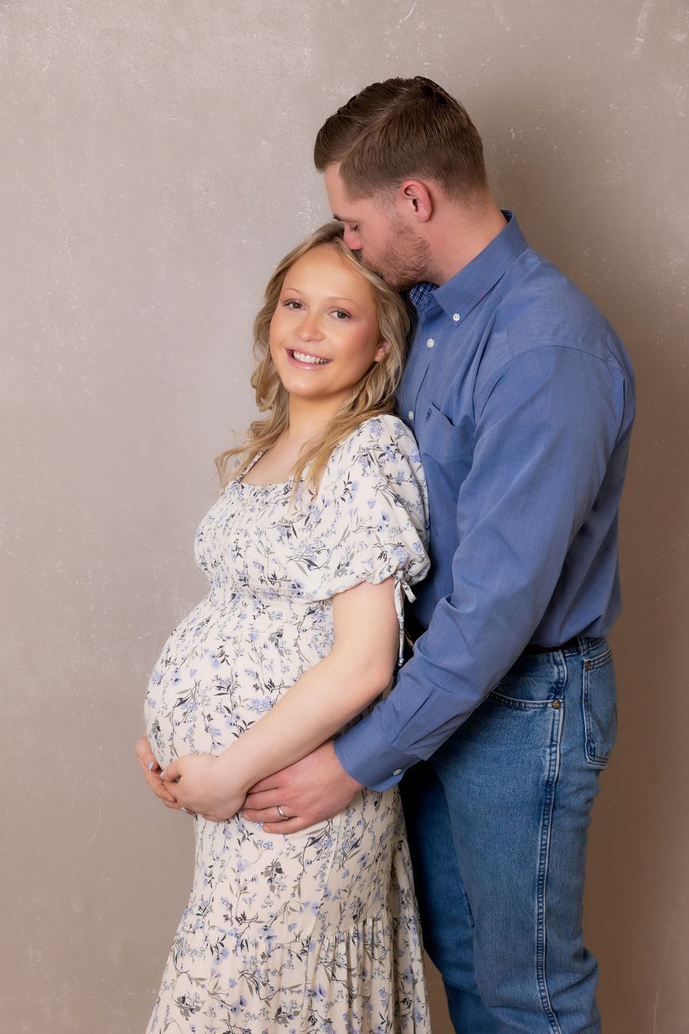 A sweet maternity portrait showing a couple in coordinated blue and floral outfits.