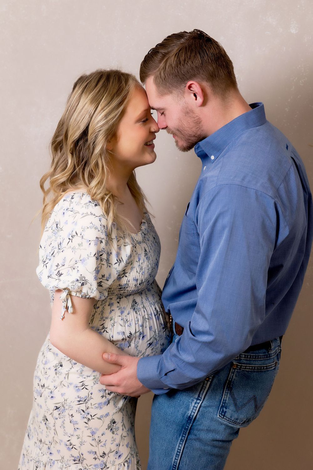 Intimate maternity portrait of couple in floral dress and blue shirt.