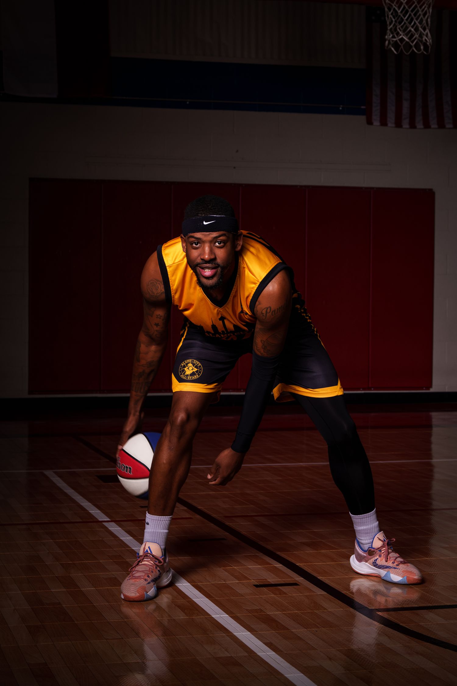 Basketball player in yellow jersey dribbles red and white ball on indoor court.