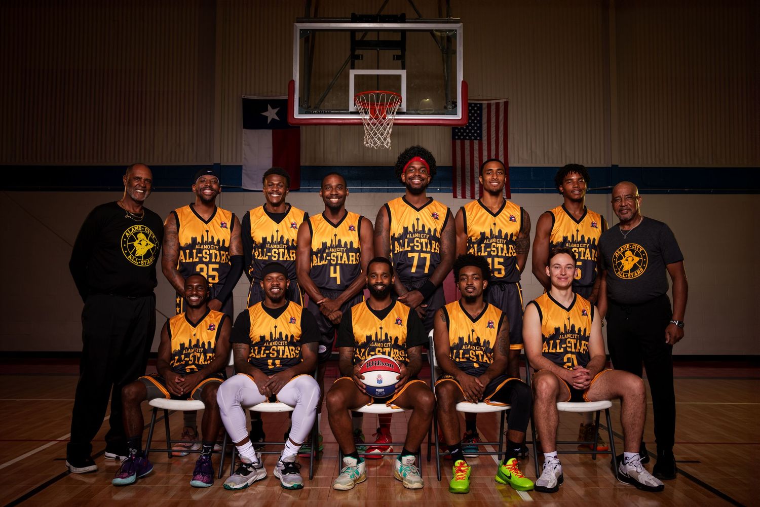 Basketball team poses for official group photo in yellow uniforms on indoor court.