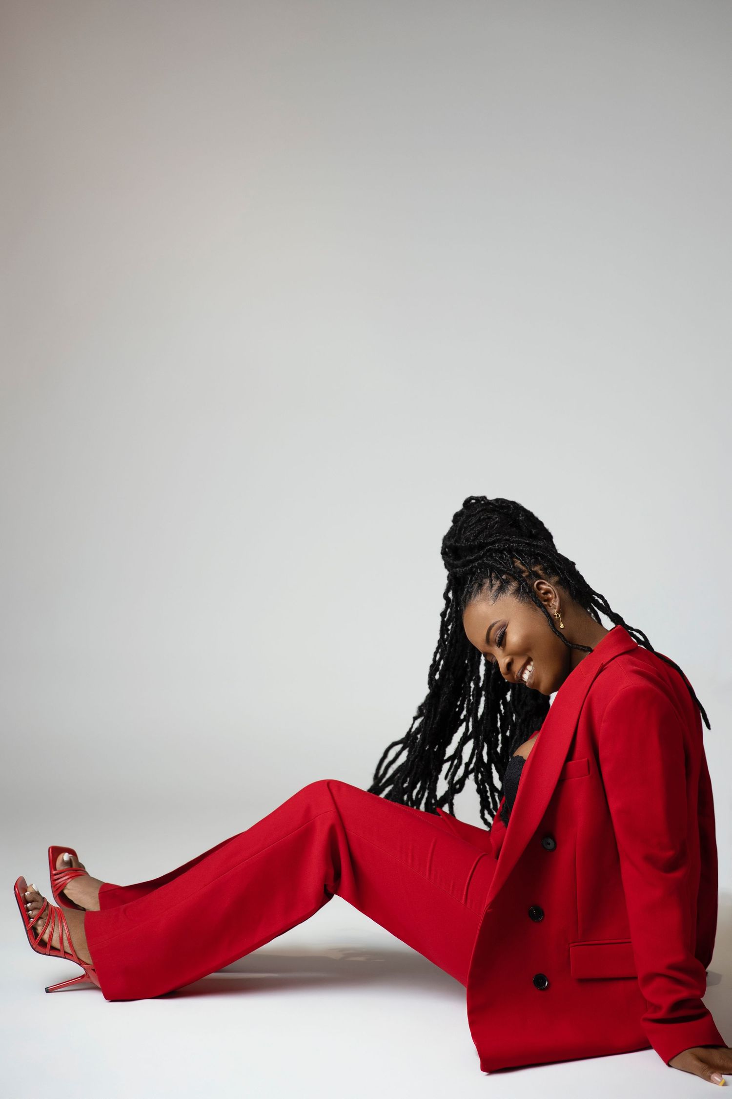 A model in a striking red pantsuit poses elegantly on a white background.